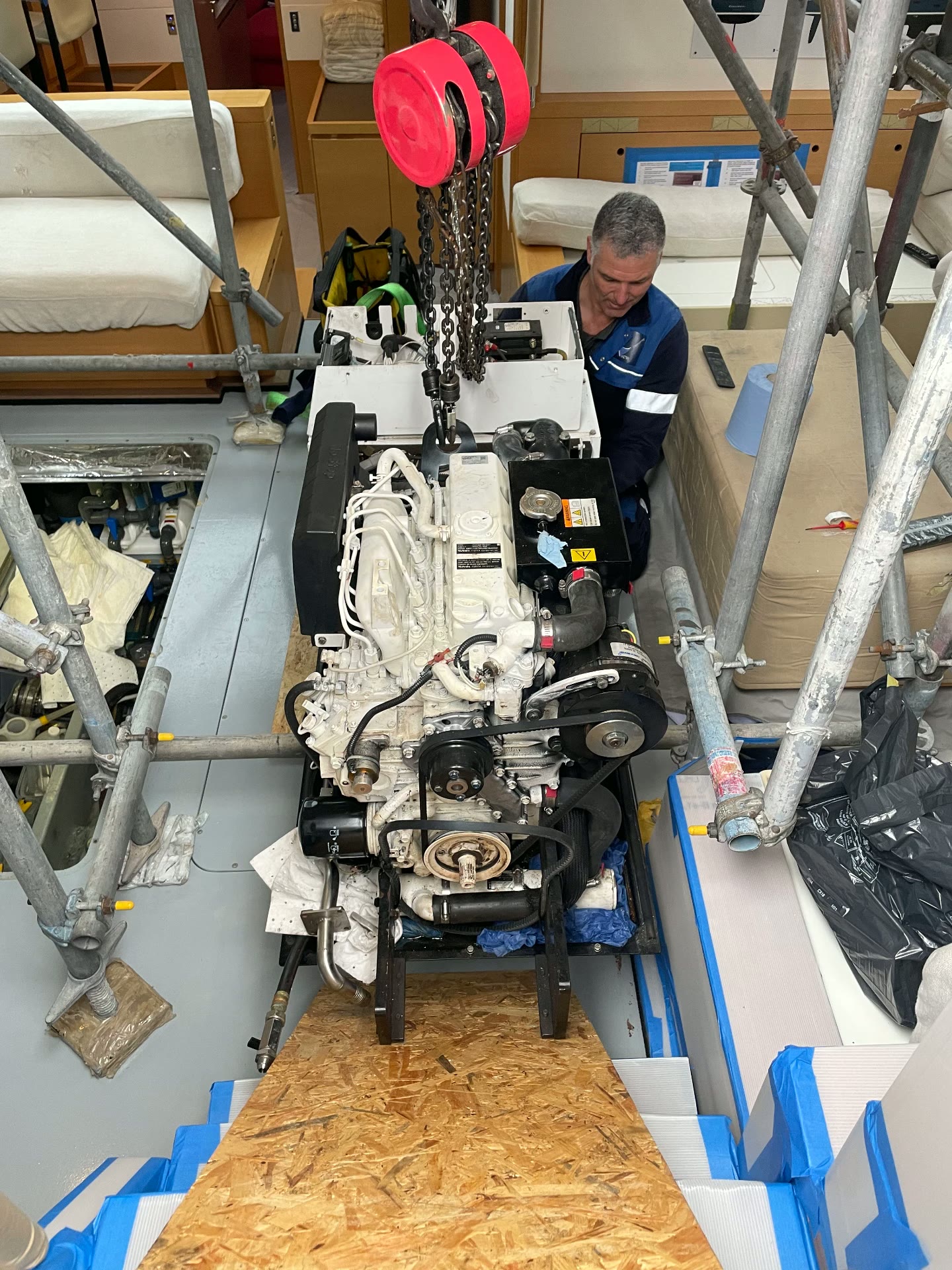 Marine engine lifted on a chain hoist through a yacht saloon during a re-power