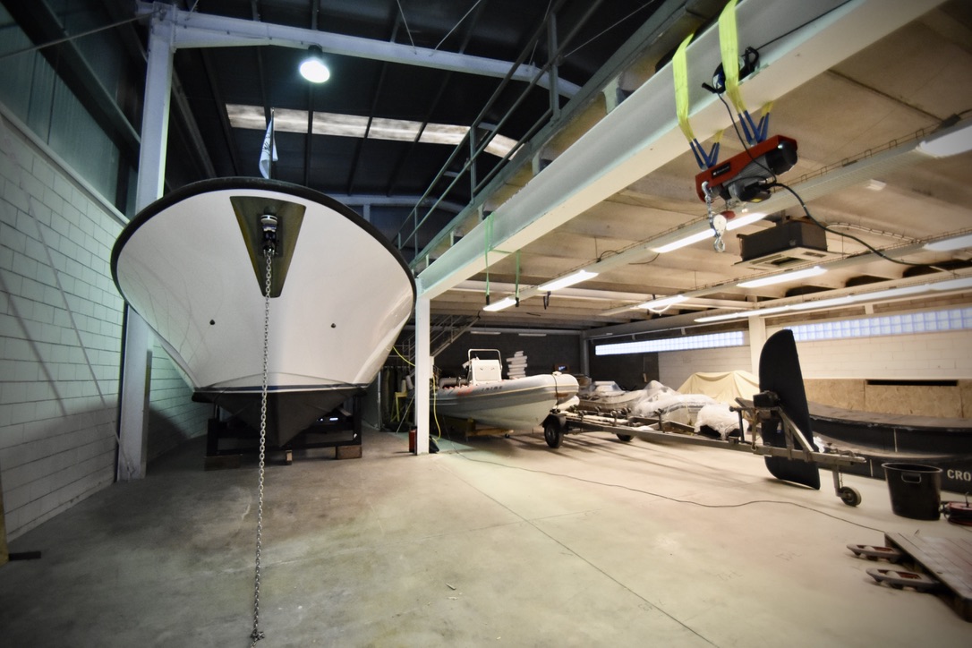 Boats and tenders stored indoors under an overhead hoist